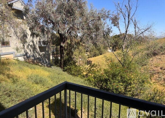 A balcony overlooks a grassy hillside with trees.