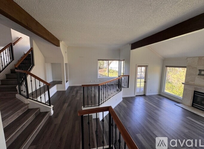A spacious living room with a fireplace and a staircase leading to the upper floor.