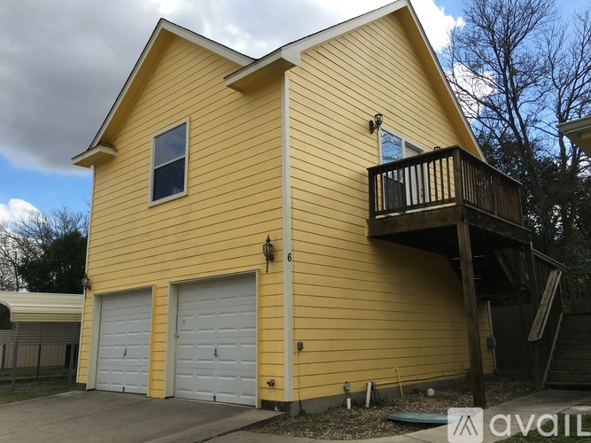 A yellow house with a balcony and two garage doors.