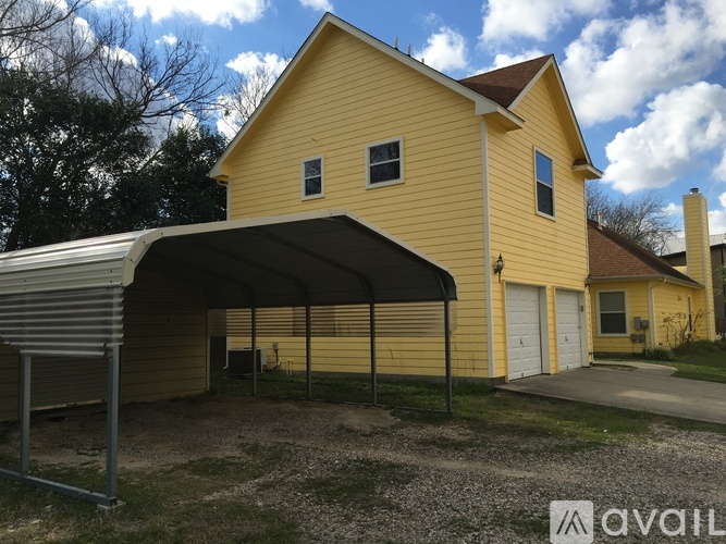 A yellow house with a garage door and a carport.