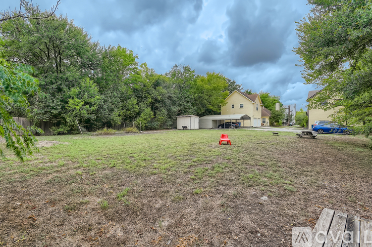 A field with a house and trees in the background.