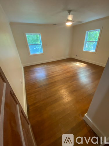 A room with wooden floors and two windows.