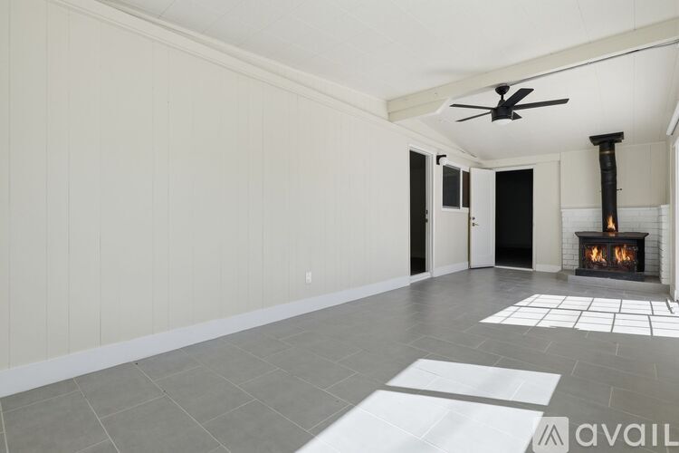 A living room with a fireplace and a fan on the ceiling.
