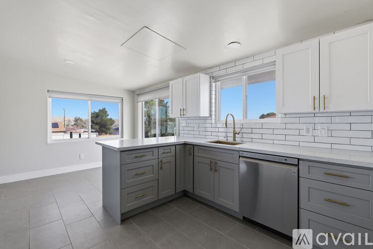 A kitchen with white cabinets and a large window.