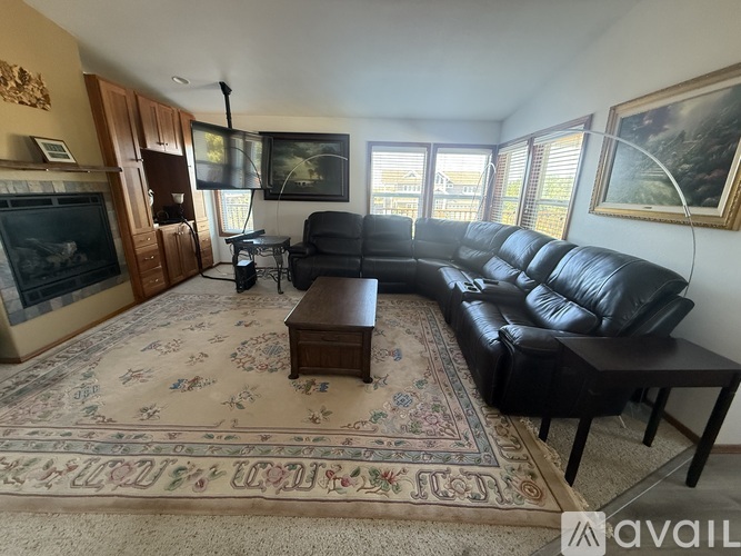A living room with a black leather couch and a rug with a floral pattern.