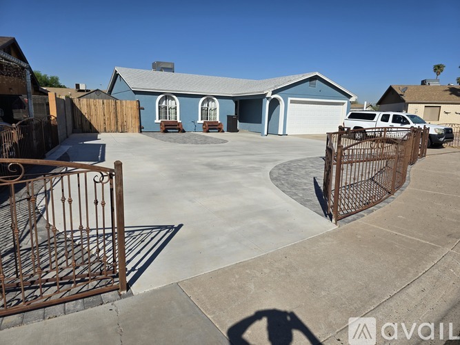 A house with a blue roof and a driveway with a gate.