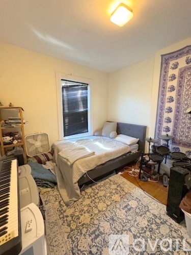 A bedroom with a bed, a keyboard, and a rug.