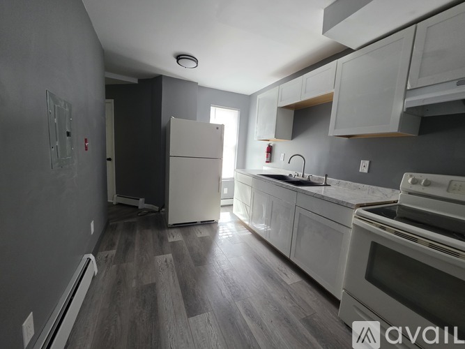 A kitchen with white appliances and wooden floors.