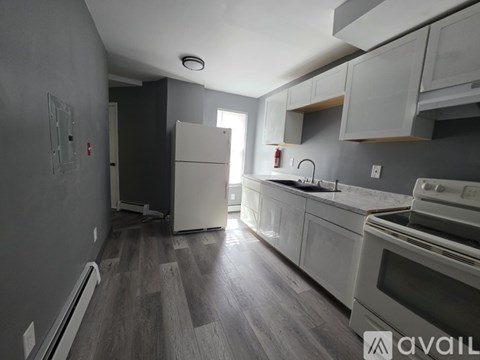A kitchen with white appliances and wooden floors.