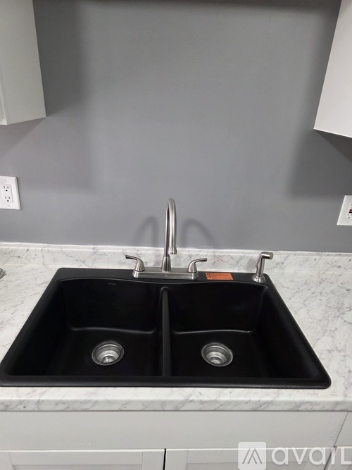 A black double sink in a marble countertop.