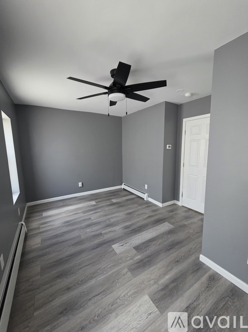 A room with a ceiling fan and wooden flooring.