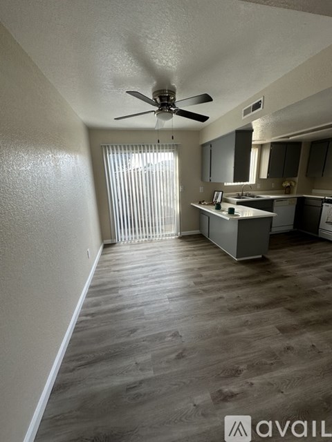 A spacious kitchen and living room with wood flooring and a ceiling fan.