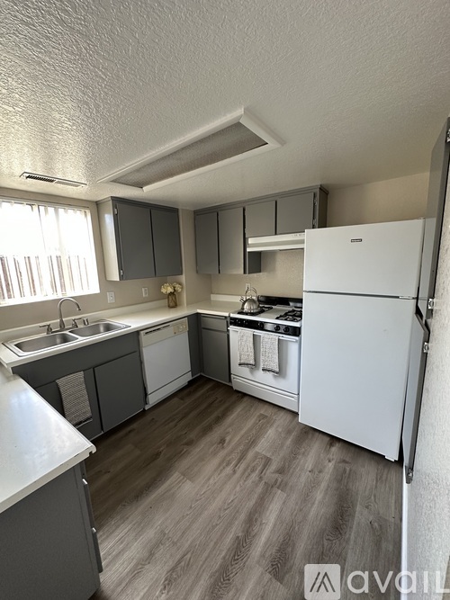 A kitchen with a white refrigerator and wooden flooring.