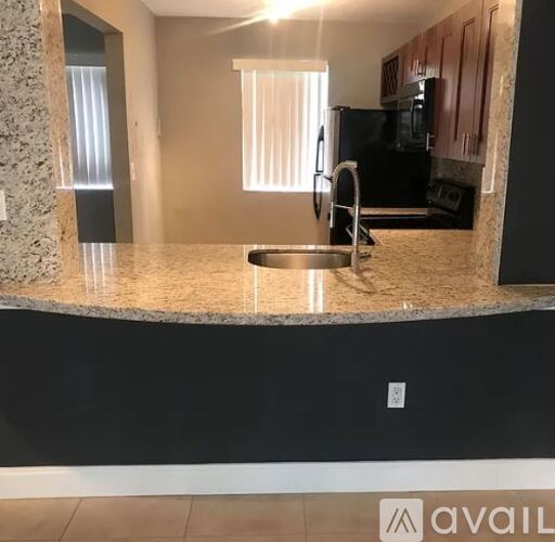 A kitchen with granite countertops and a black refrigerator.