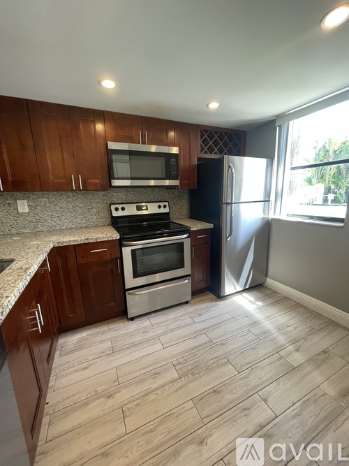 A kitchen with wooden cabinets and a stainless steel refrigerator.