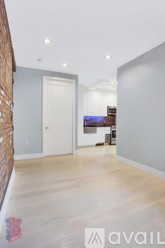 A room with a white door and a brick wall on the left side.