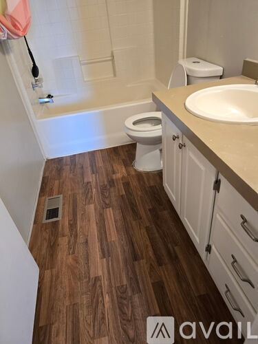 A bathroom with a wooden floor and white walls.