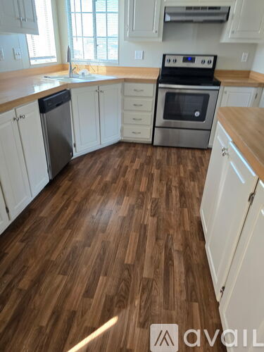 A kitchen with wooden flooring and white cabinets.