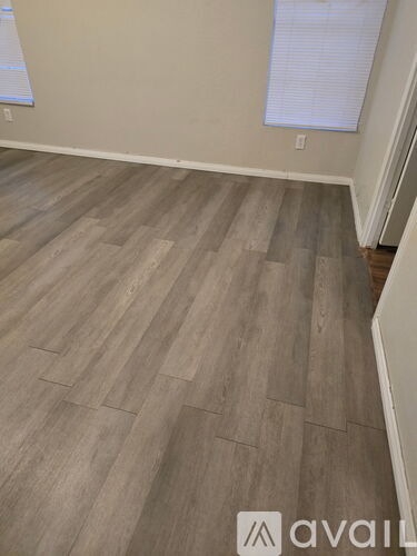 A room with wooden flooring and a window with blinds.