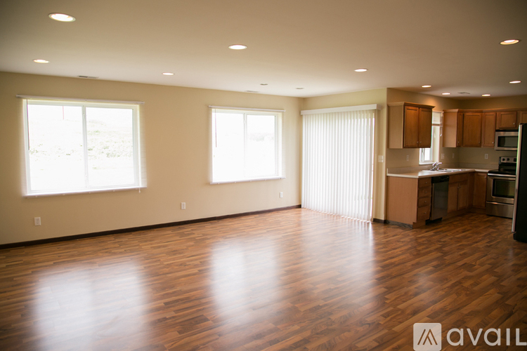 A spacious room with wooden floors and large windows.