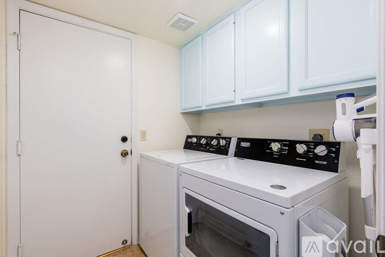 A white door is open to a kitchen with a white oven and white cabinets.