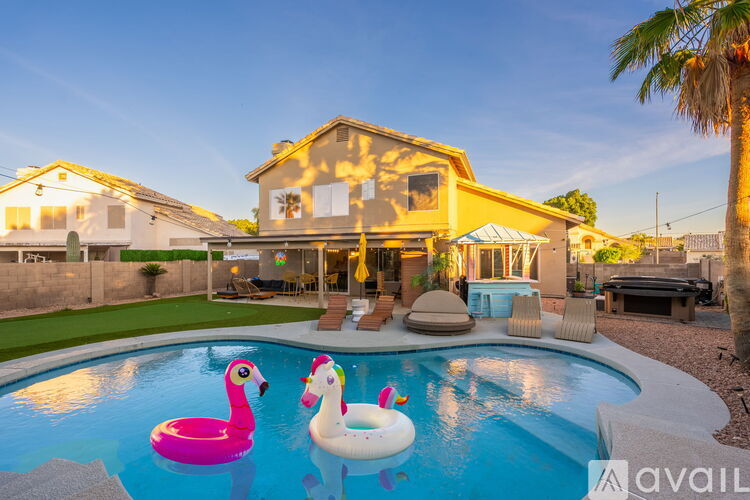 A house with a pool and inflatable flamingo floaties.
