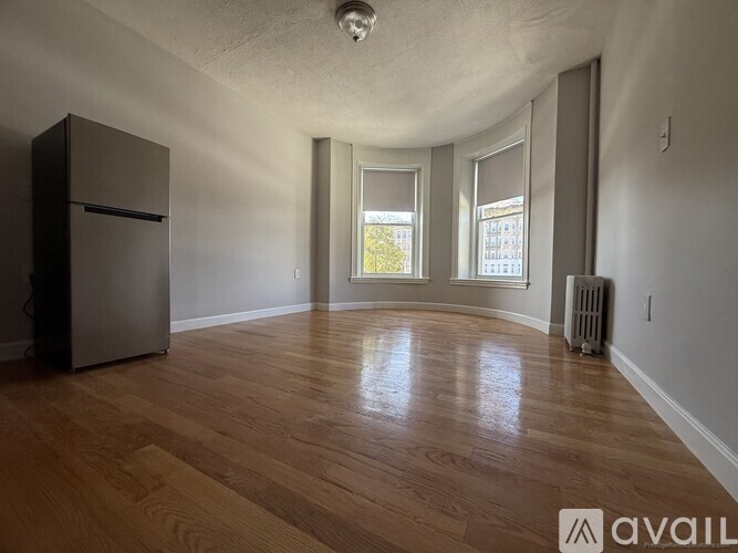 A room with wooden flooring and a refrigerator.