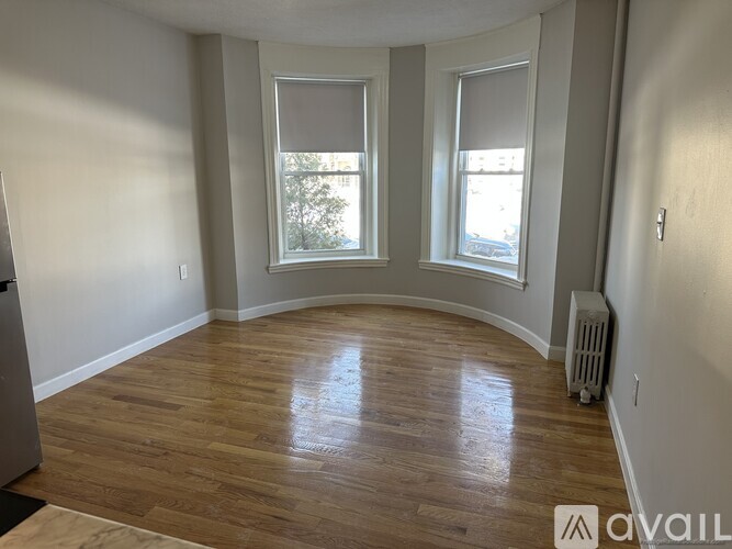 A room with wooden flooring and two windows.