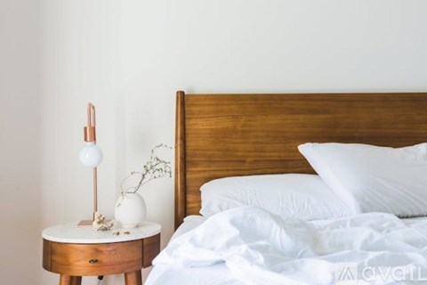 A bed with white pillows and a wooden headboard is in the image.