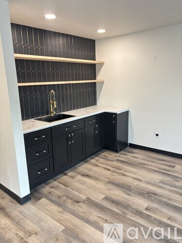 A kitchen with black cabinets and a wooden floor.