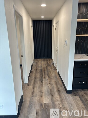 A hallway with wood flooring and white walls.