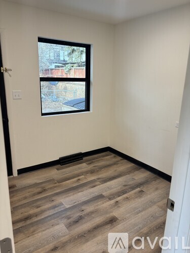 A room with a window and wooden flooring.