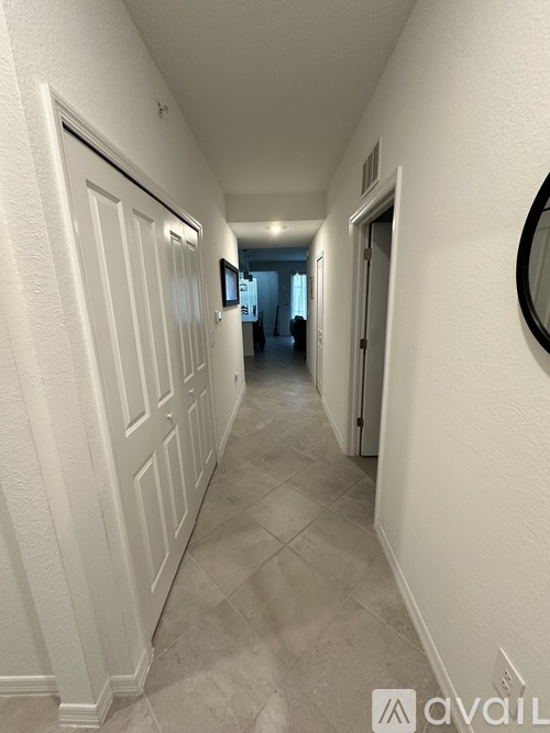A long hallway with white doors and a mirror on the wall.
