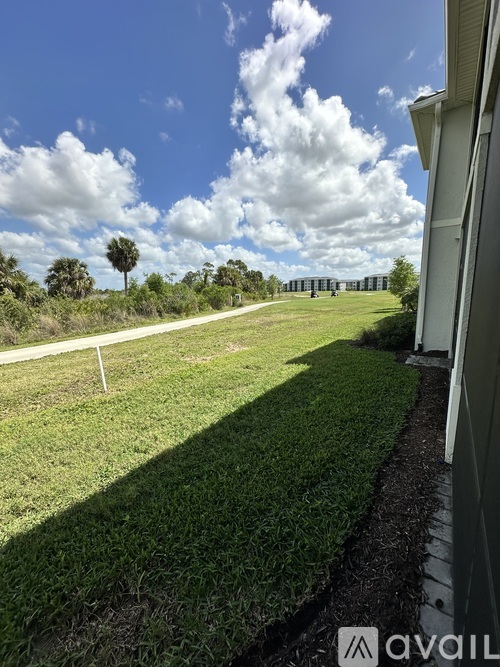 A grassy area with a white fence and a building on the right side.