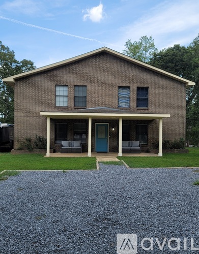 A brick house with a gravel driveway in front.