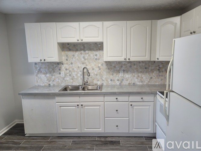 A kitchen with white cabinets and a marble backsplash.