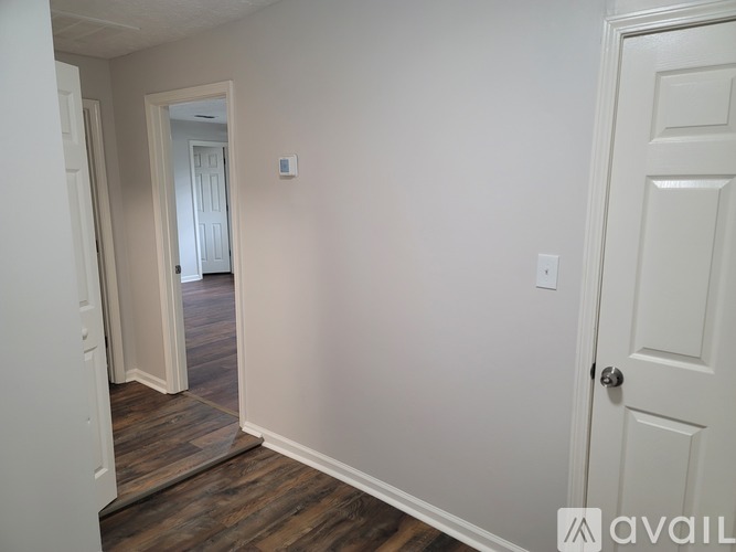 A room with a white door and a white wall with a switch.