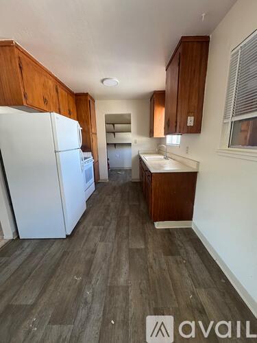 A kitchen with a white fridge and wooden cabinets.