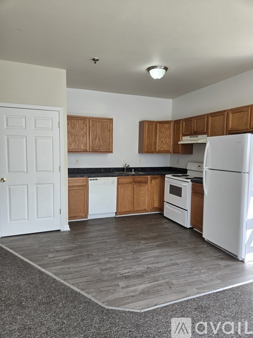 A kitchen with white appliances and brown cabinets.
