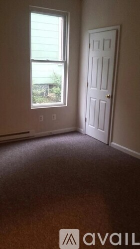 A room with a carpeted floor, a door and a window.