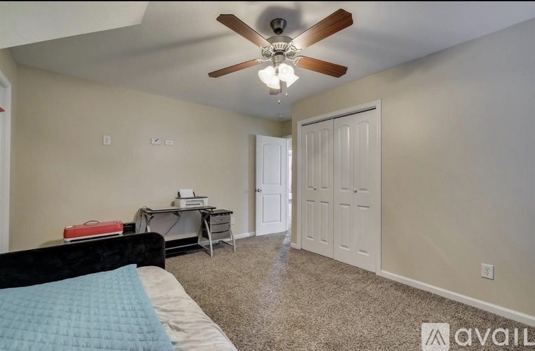 A bedroom with a bed, desk, and closet.