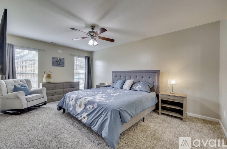 A bedroom with a bed, chair, and ceiling fan.
