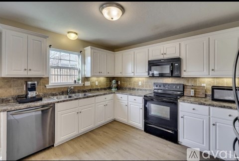 A kitchen with white cabinets and a black oven.