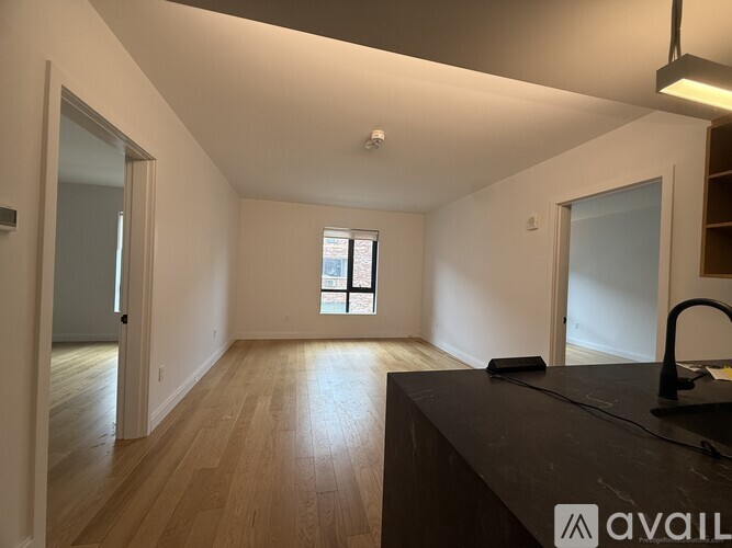A spacious room with wooden floors and a large window.