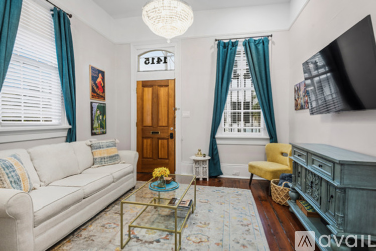 A living room with a white sofa, a coffee table, and a flat screen TV mounted on the wall.