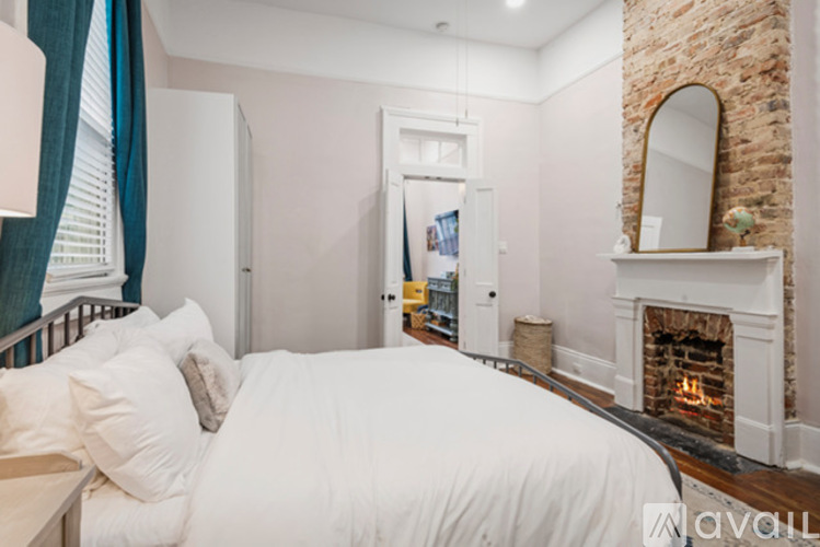 A bedroom with a white bed and a fireplace.