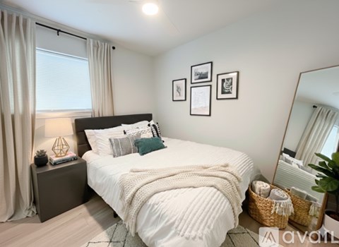A bedroom with a large bed, a nightstand with a lamp, a mirror, and pictures on the wall.