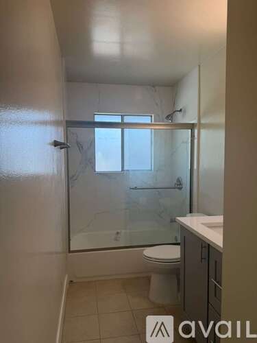 A small bathroom with a toilet, sink, and shower.
