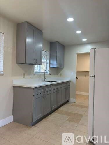 A kitchen with grey cabinets and a white counter top.
