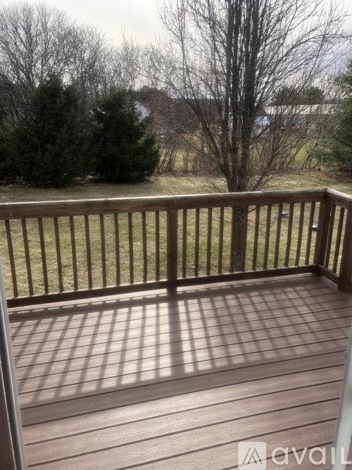 A deck with a railing and a view of a grassy area.